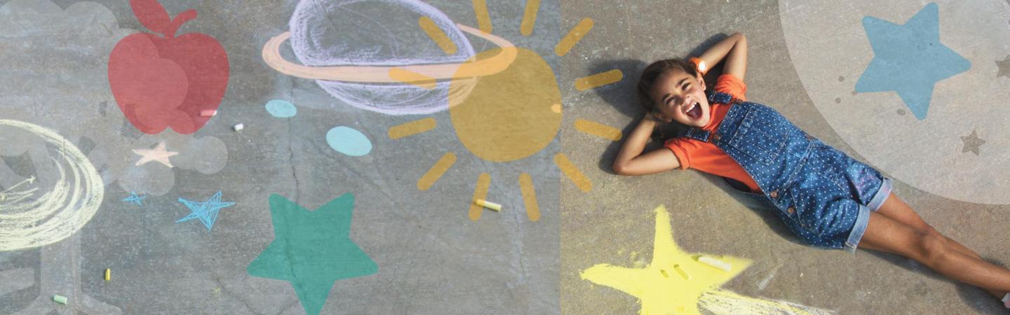Photo of a child laying in front of sidewalk chalk drawings.